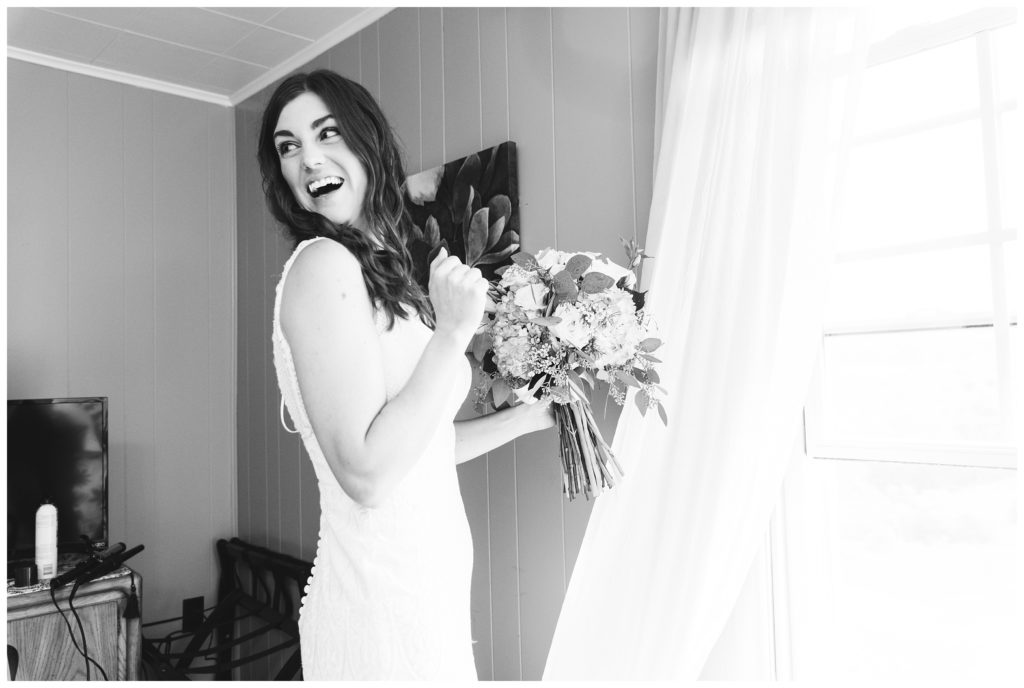 black and white photo of bride holding bouquet in front of window at the farm house inn
