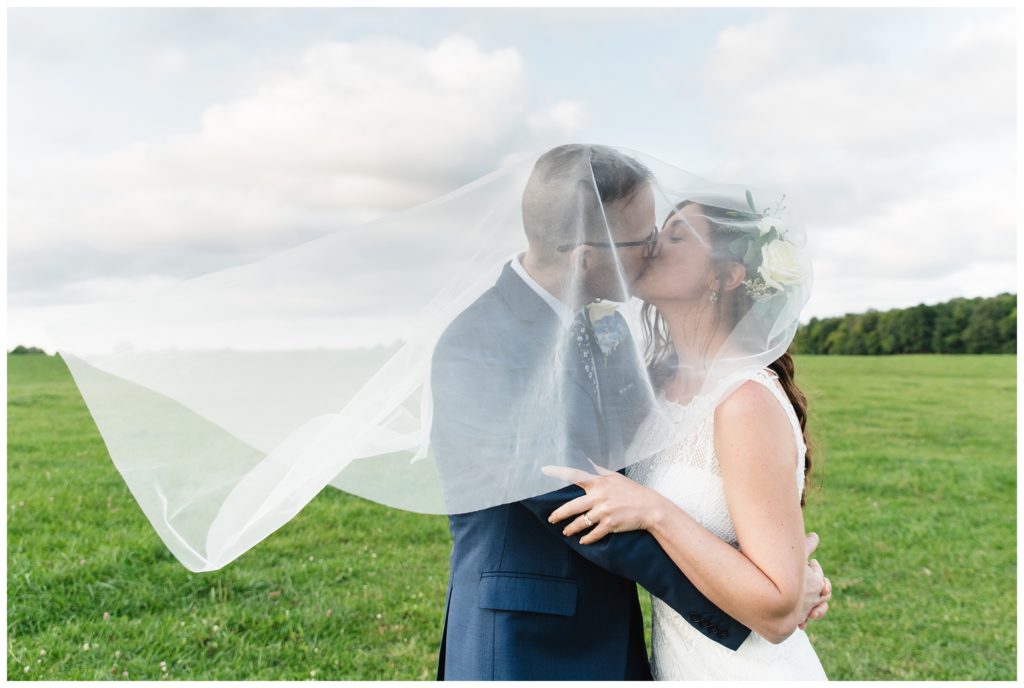 bride and groom kissing with veil in wind at the farm house inn