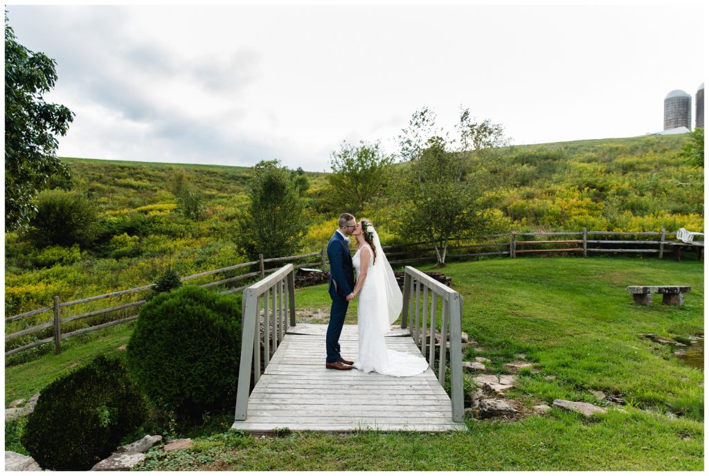 bride and groom kissing on bridge at the farm house inn
