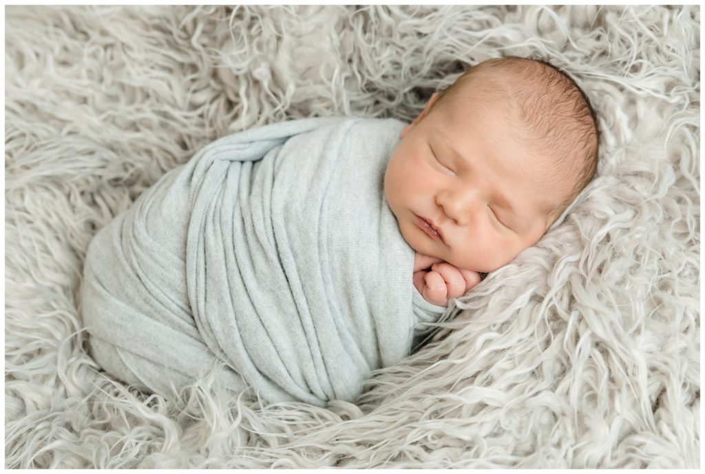 newborn wrapped in gray on gray fur at bridgeville newborn photographer studio