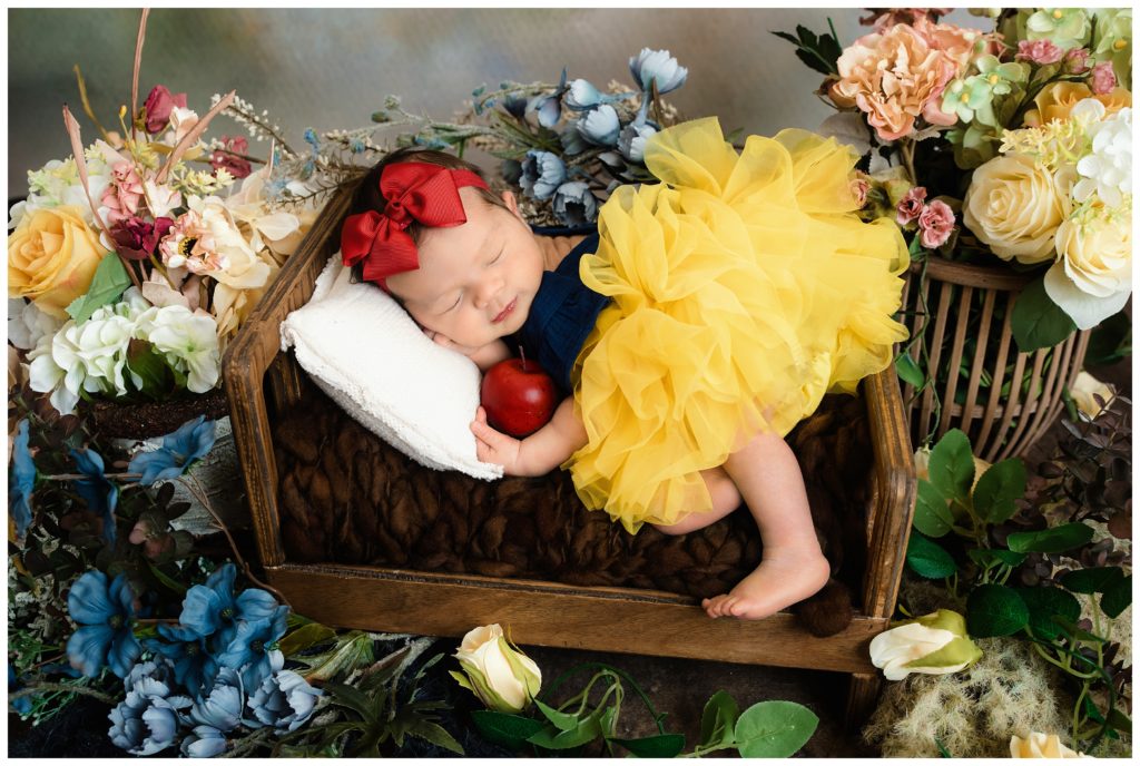 newborn girl in snow white outfit with red bow