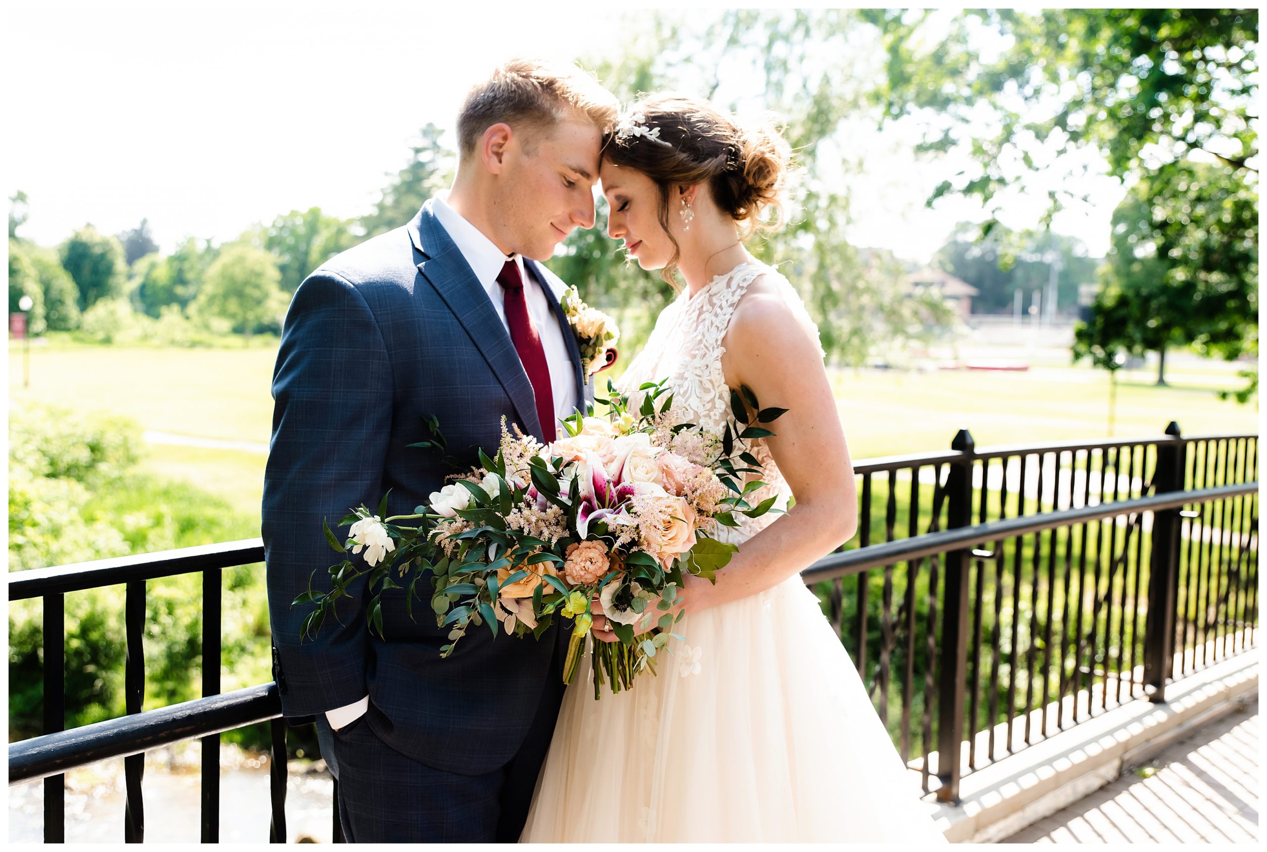 bride and groom touch foreheads on bridge at grove city college