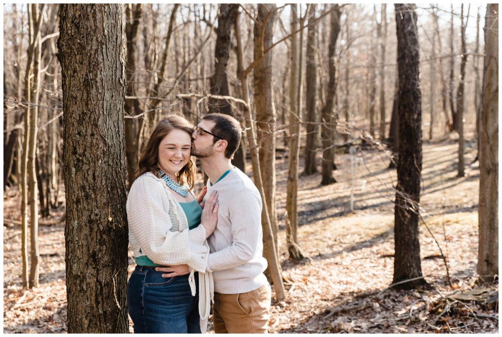 engaged couple kissing in woods
