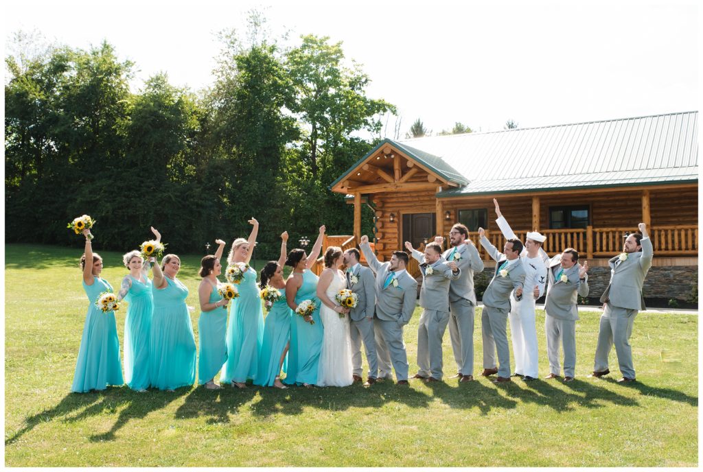 bride and groom kissing with bridal party celebrating
