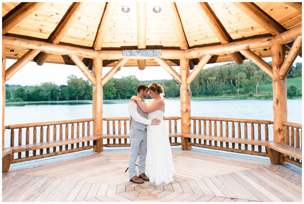 bride and groom lean into each other with lake behind them