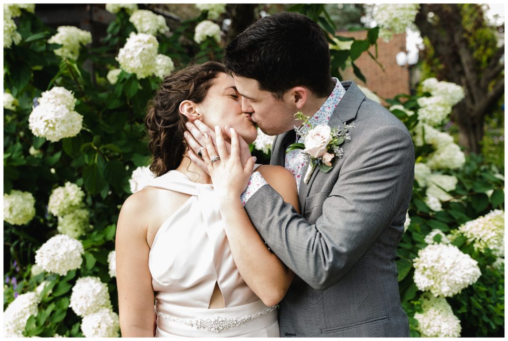 bride and groom kissing in front of flowers