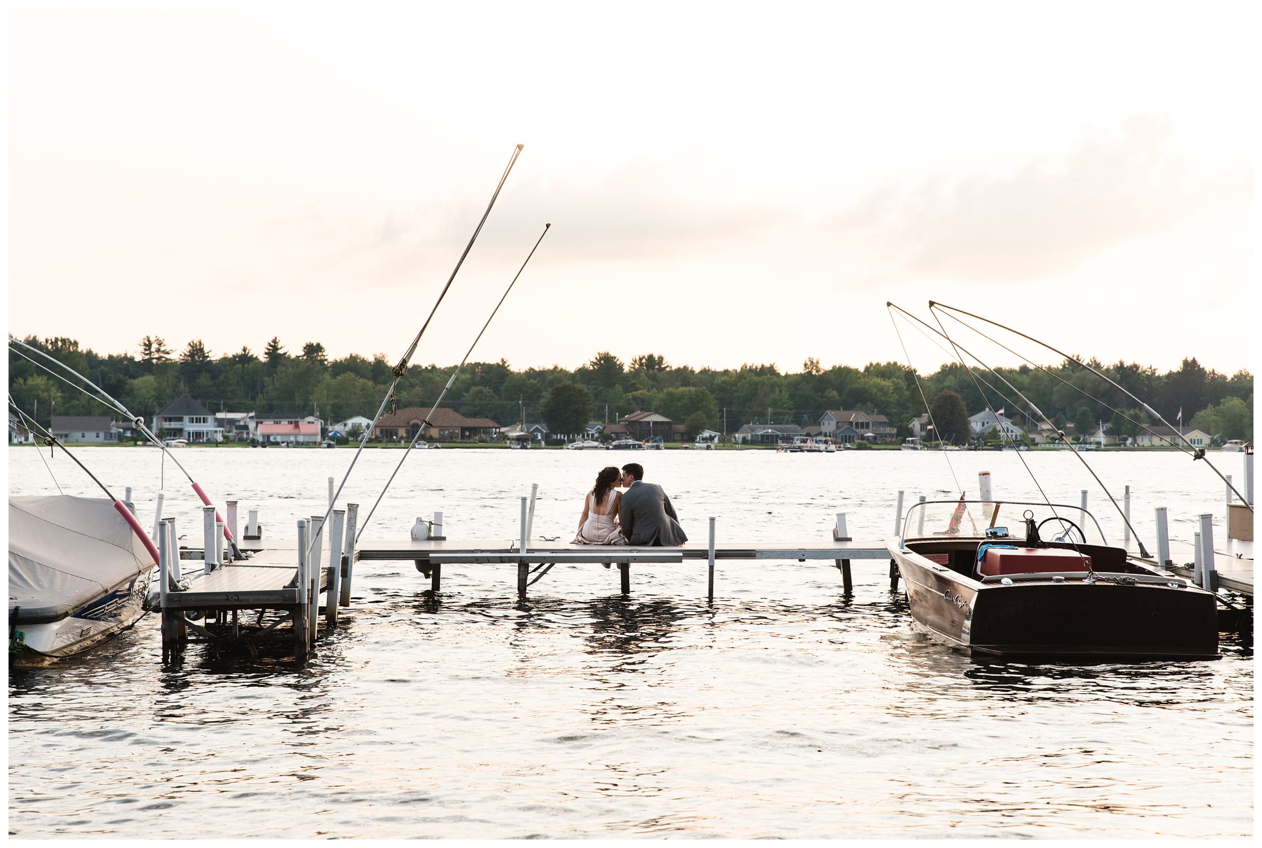 bride and groom kissing on dock at sunset
