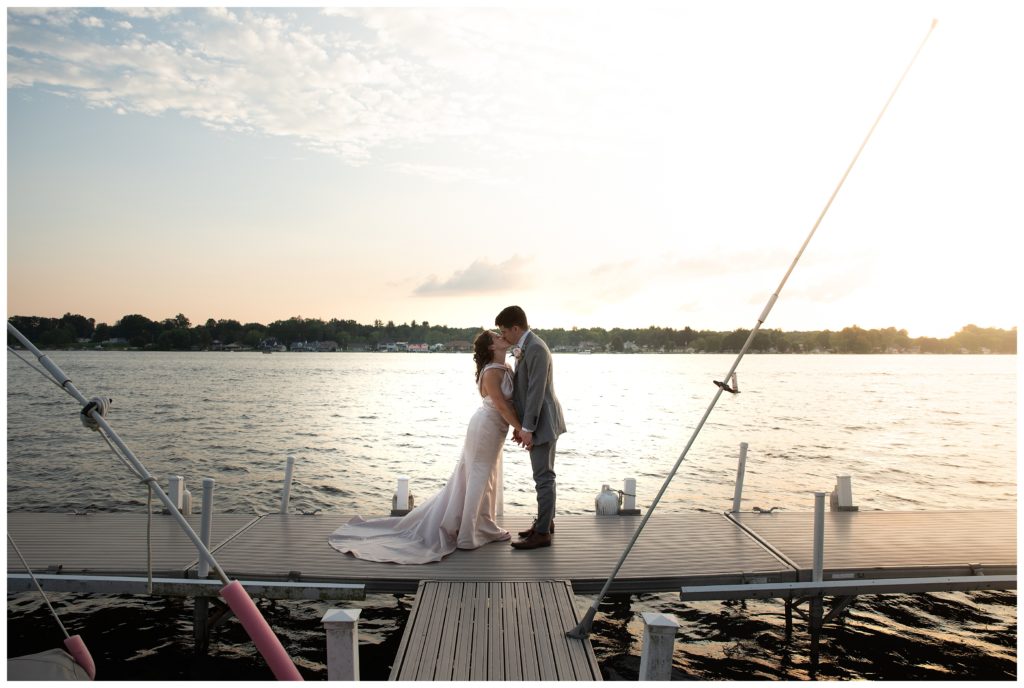  bride and groom kissing on dock at sunseet