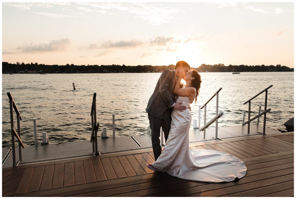 groom dipping bride on dock at sunset
