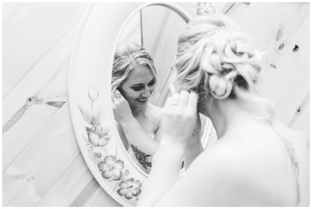 black and white of bride putting on earring