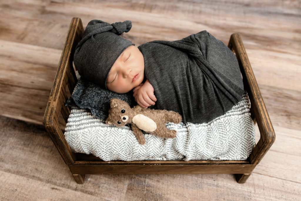 newborn boy sleeping in tiny wooden bed with stuffed  bear | best pittsburgh newborn photographer