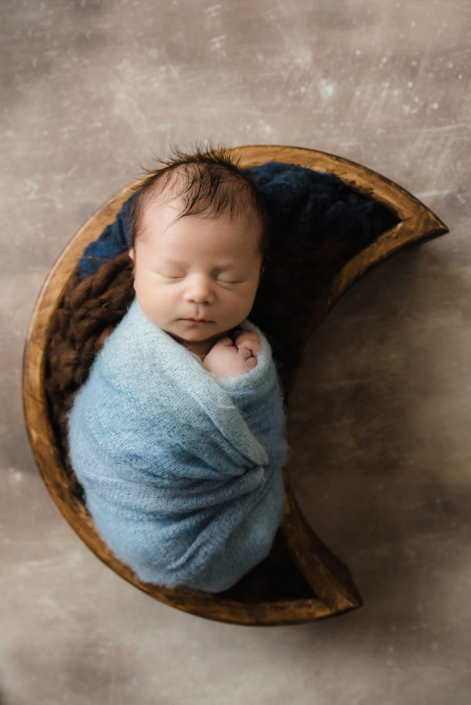 Newborn boy sleeping in cute wooden moon bowl wrapped in blue | Pittsburgh Newborn Photographer