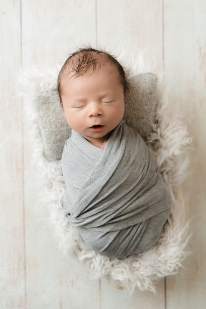 Newborn boy in gray wrap sleeping on pillow | Pittsburgh Newborn Photographer