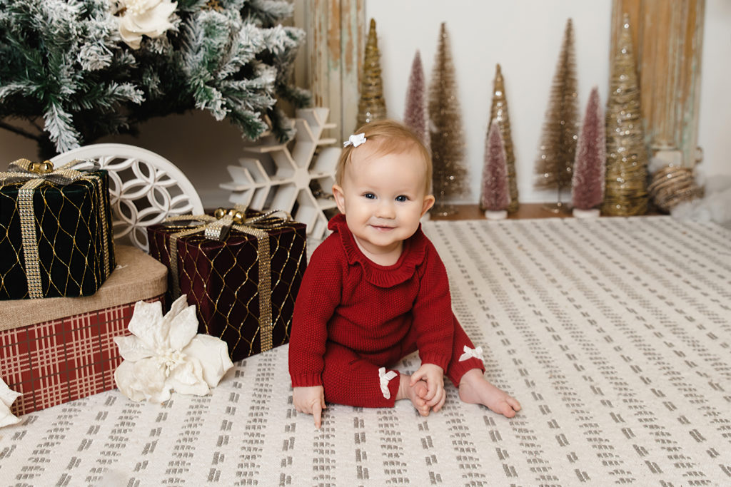 baby girl sitting in front of christmas tree
