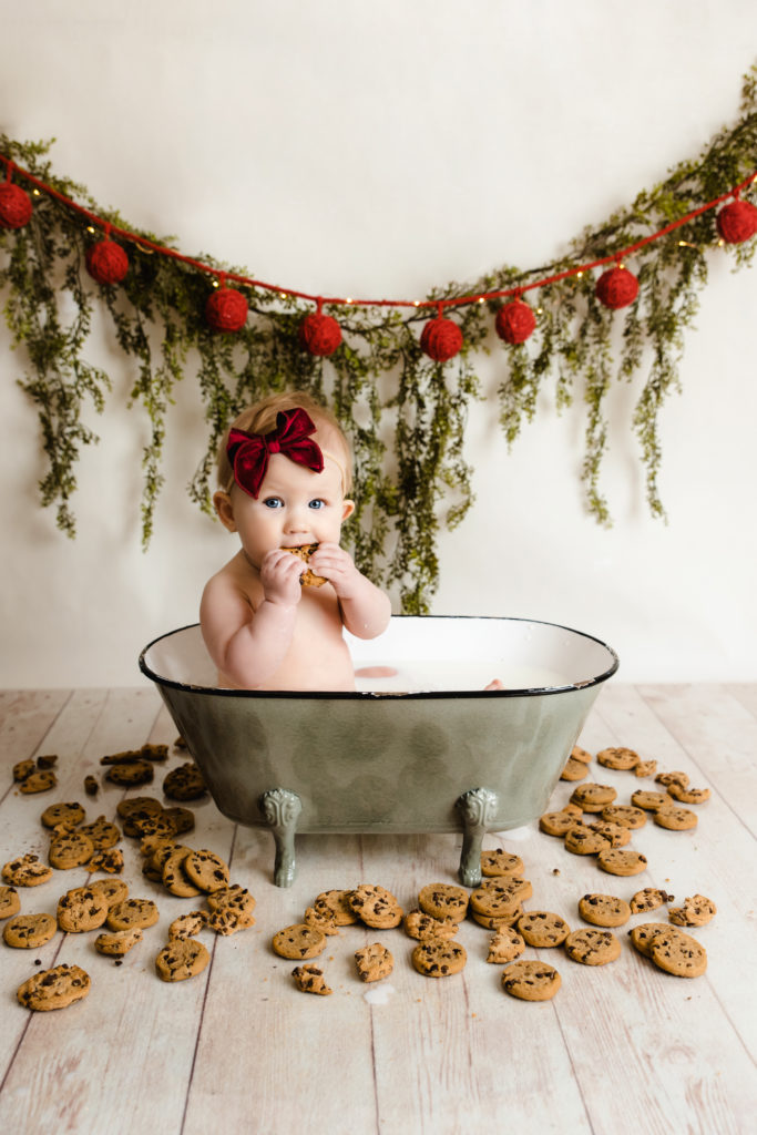 baby girl in tub filled with milk surrounded by chocolate chip cookies