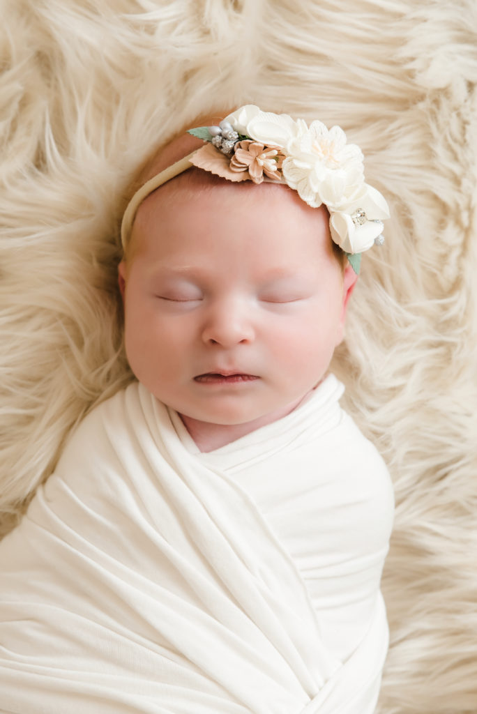 newborn girl sleeping on cream blanket