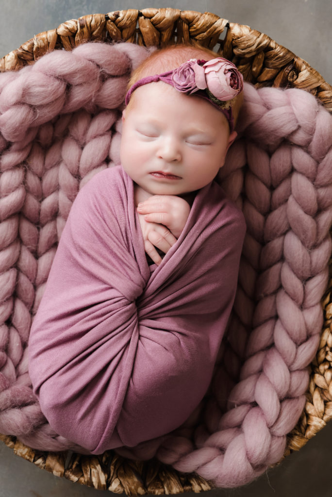 closeup of newborn girl sleeping in round basket