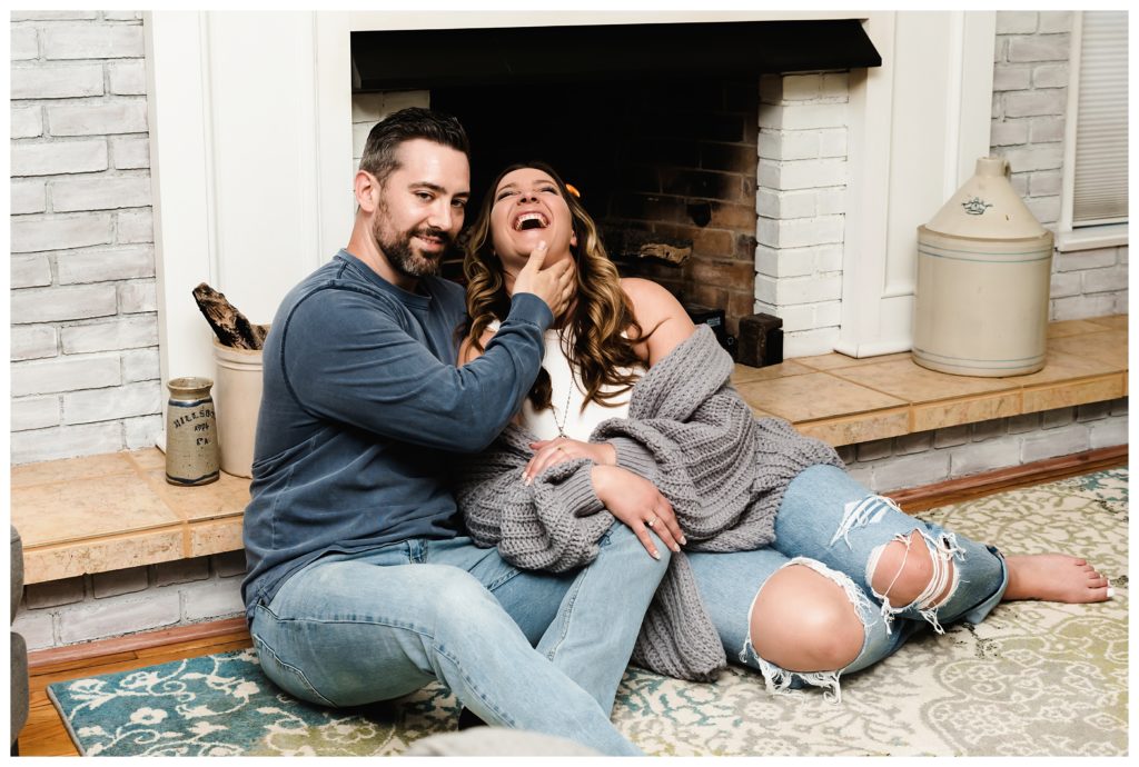 engage couple acting silly by fireplace - cozy home engagement session