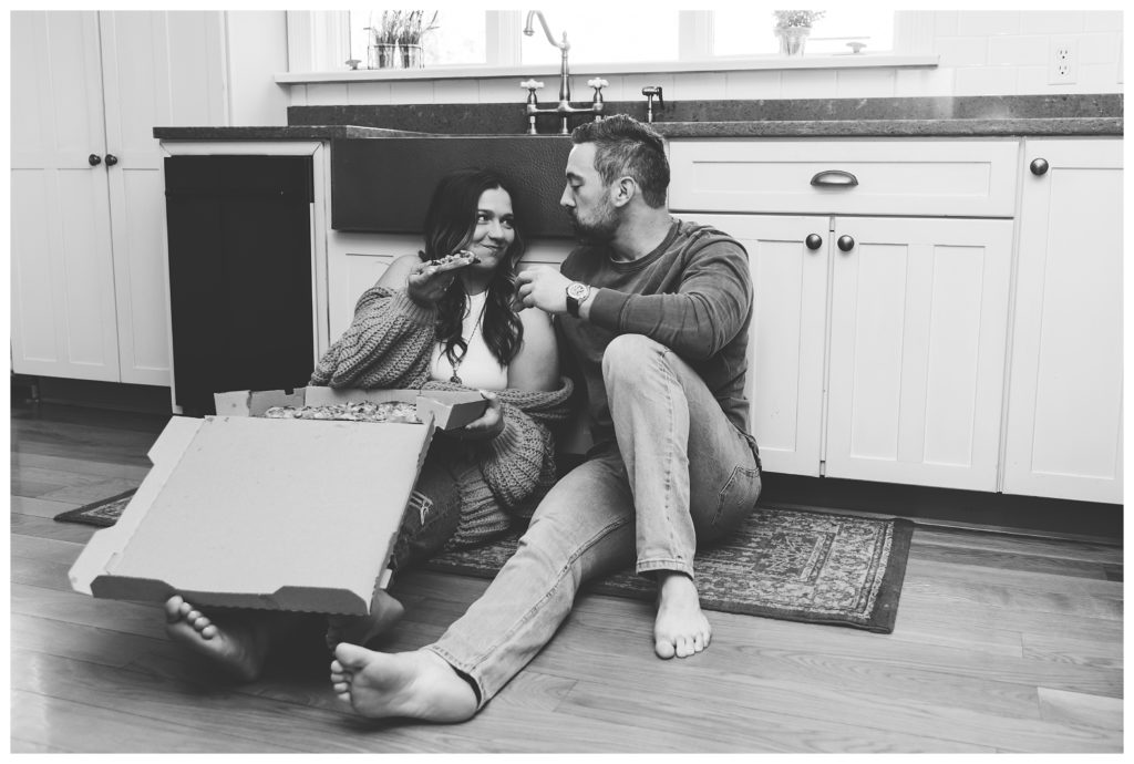 black and white image of engaged couple toasting pizza slices - cozy home engagement session