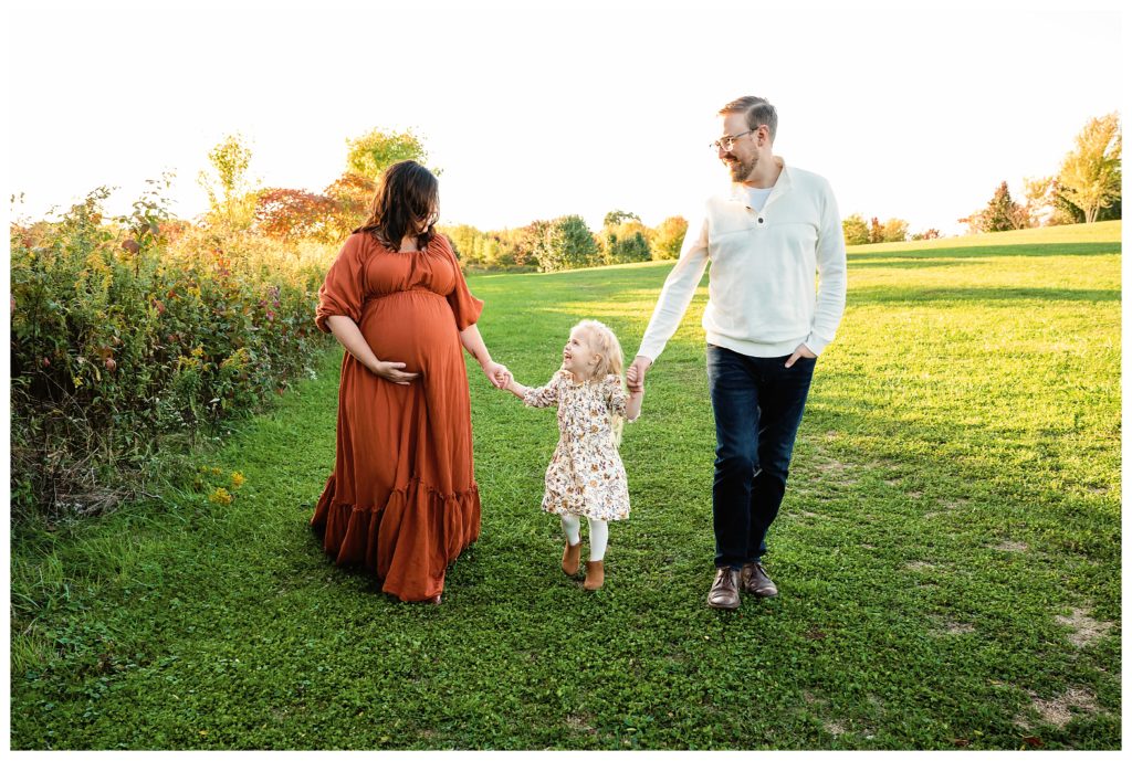 Family walks hand in hand during maternity session in Bridgeville, PA.