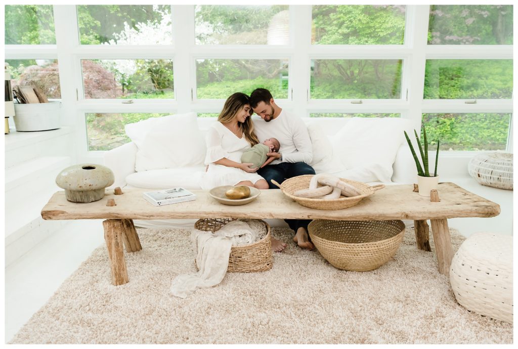 Parents snuggle with baby on couch for lifestyle newborn photoshoot in Pittsburgh, PA.