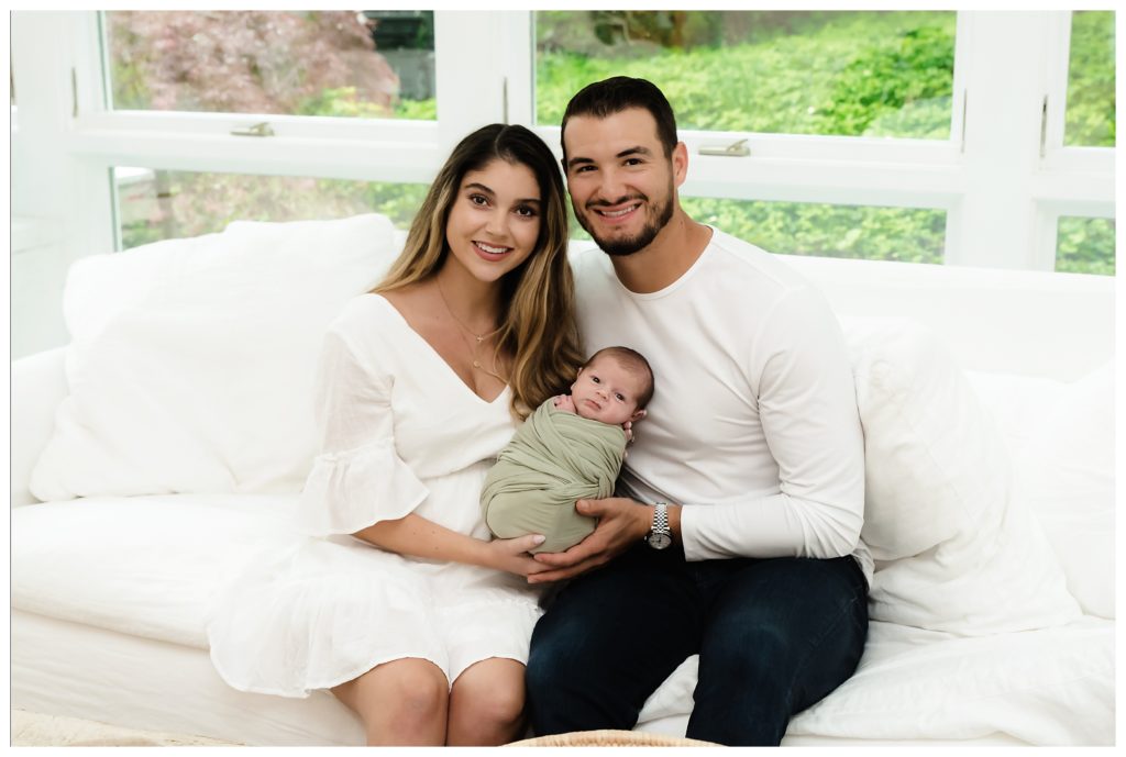Mitch and Hillary Trubisky sit on couch holding baby Hudson during at-home lifestyle newborn session in Pittsburgh, PA.
